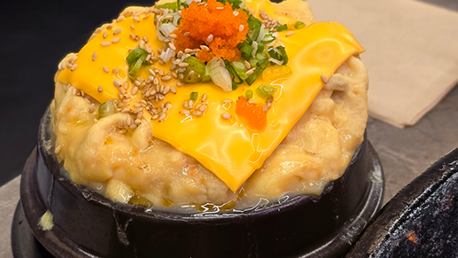 돌솥에 담긴 치즈 토핑 계란찜, 위에 날치알과 파, 깨가 올려져 있음