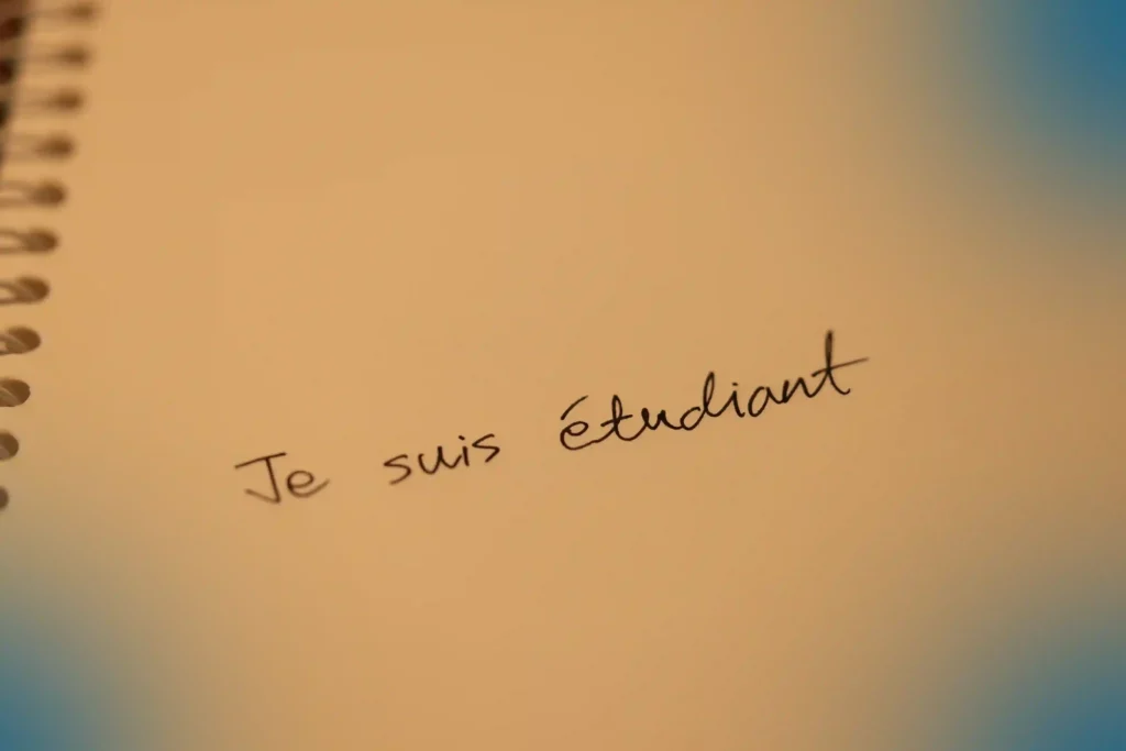 프랑스어 문장 "Je suis étudiant"를 노트에 손글씨로 적은 모습