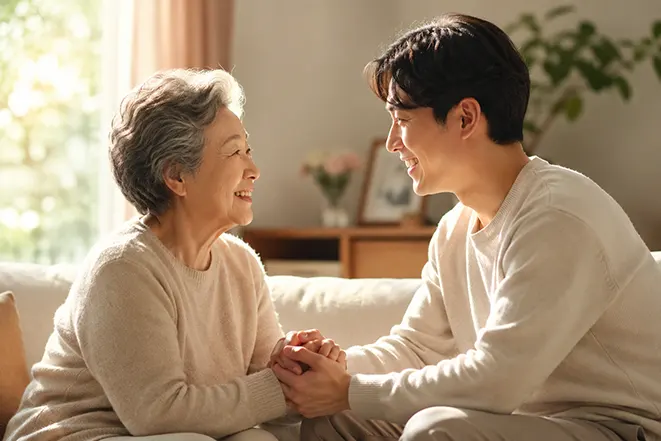 따뜻한 거실에서 어머니와 아들이 손을 맞잡고 서로를 바라보며 웃고 있는 효도와 가족 사랑 이미지